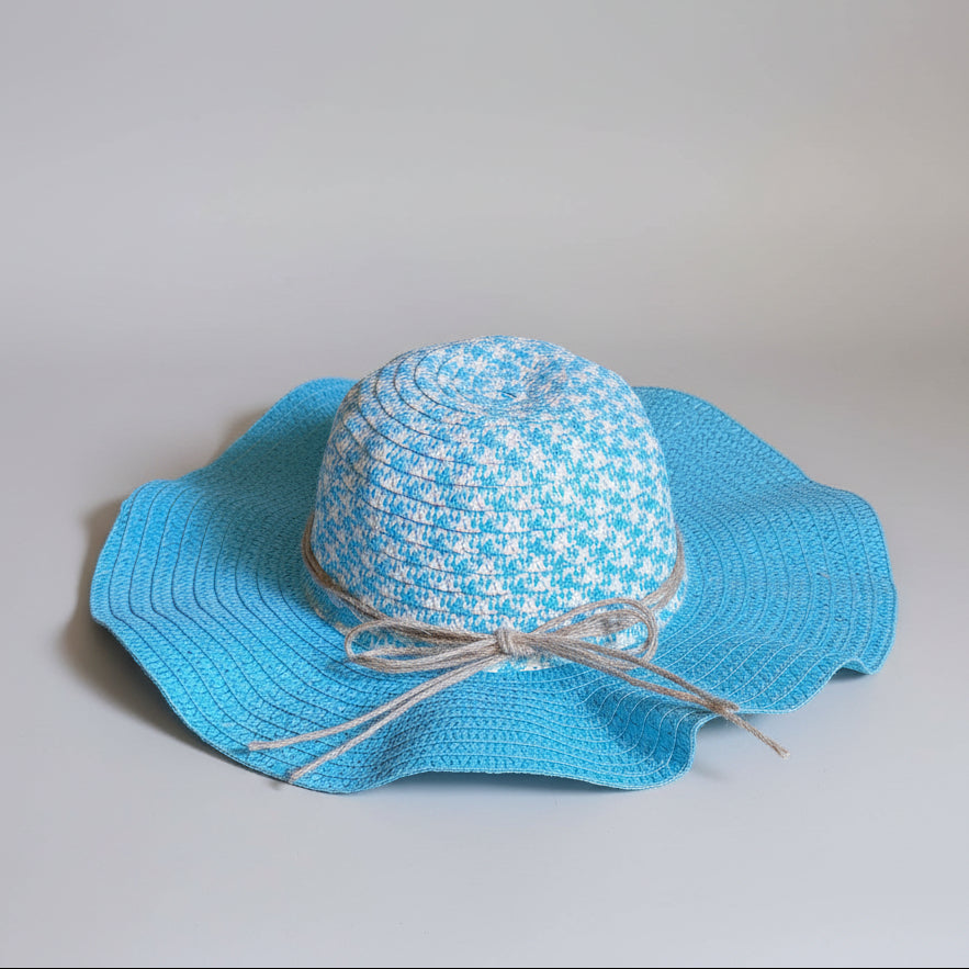 A light blue and white patterned sun hat with a gray bow, resting on a brown cardboard box.