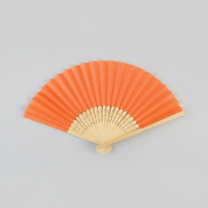 An orange folding hand fan with a light natural wood frame, shown partially open against a solid light gray background.