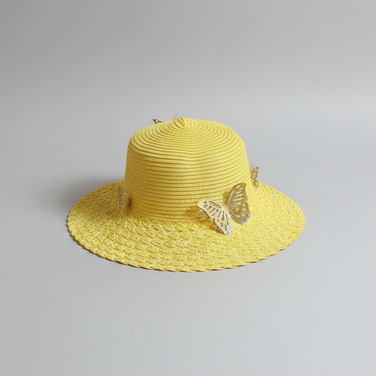 A yellow woven straw hat with a decorative white butterfly ornament on the brim, resting on a brown cardboard box.