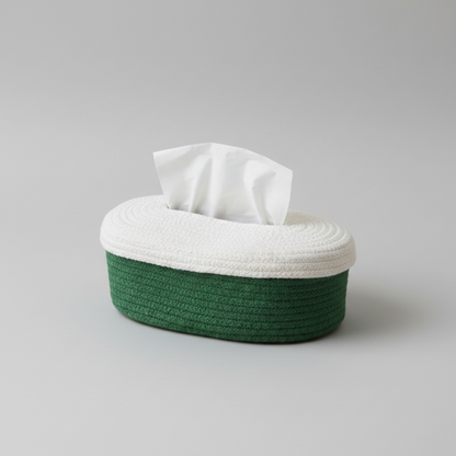 An oval tissue box cover with a woven dark green base and a white top, with white tissue paper protruding from the top, photographed on a neutral gray background.
