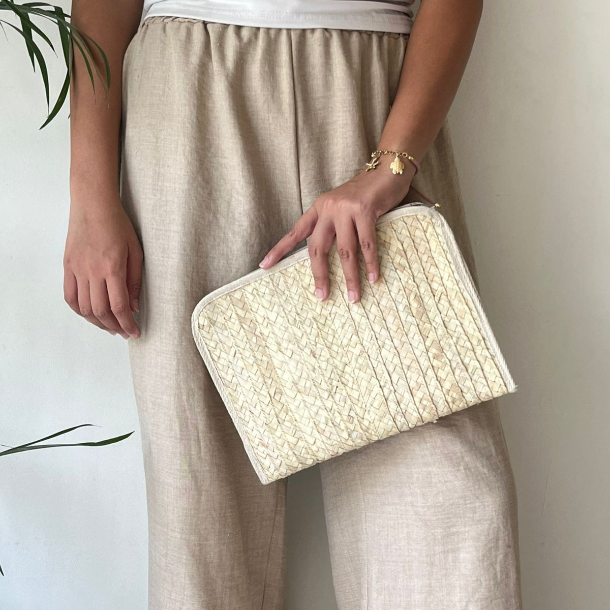 Baseta palm pouch held flat at the hip by a woman in a neutral outfit, showing its size and shape — Khoos