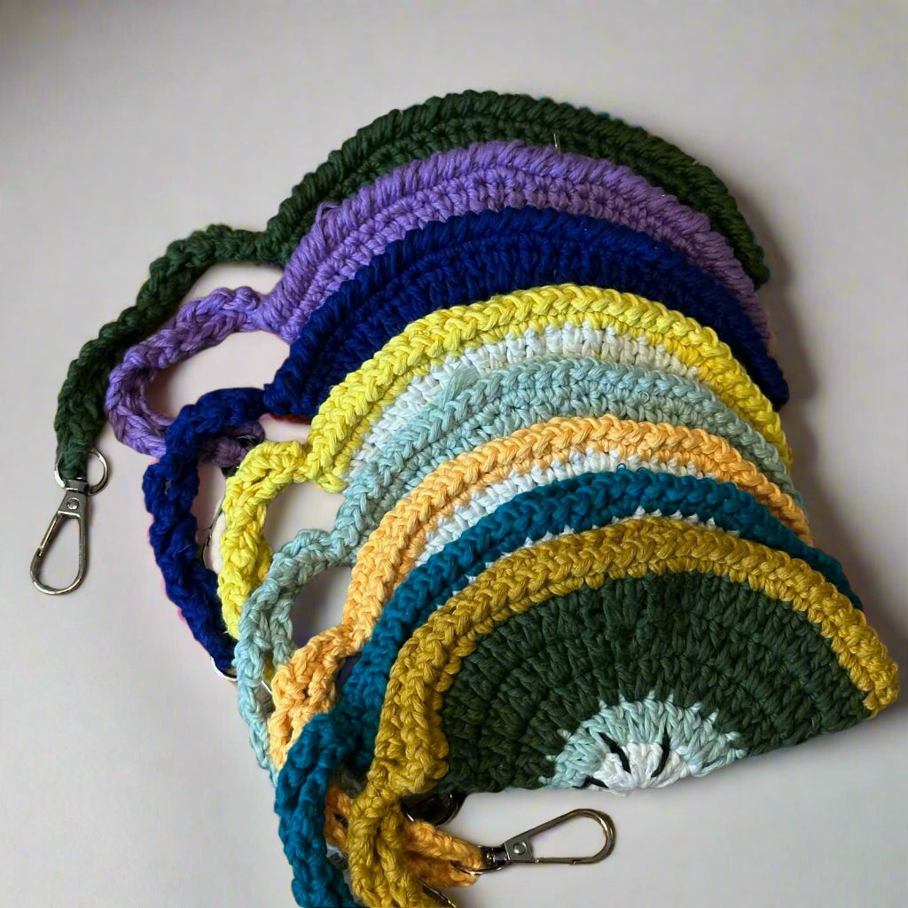 Hand-crocheted cotton sunglasses cases in all nine colourways fanned out, each with a wrist strap and clip — Khoos