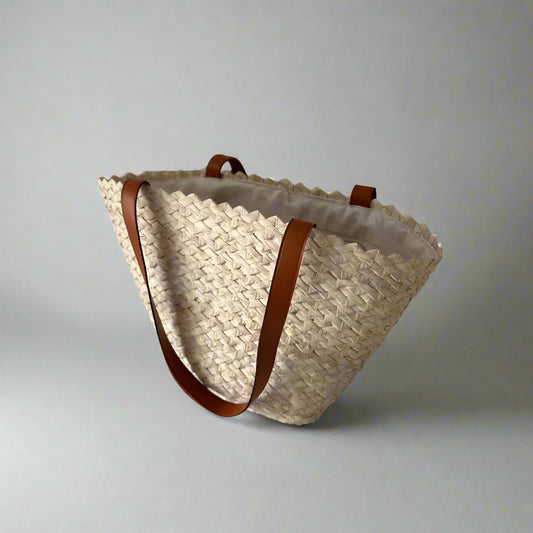 Eco-Chic handwoven palm tote with tan leather handles on a plain studio backdrop — Khoos
