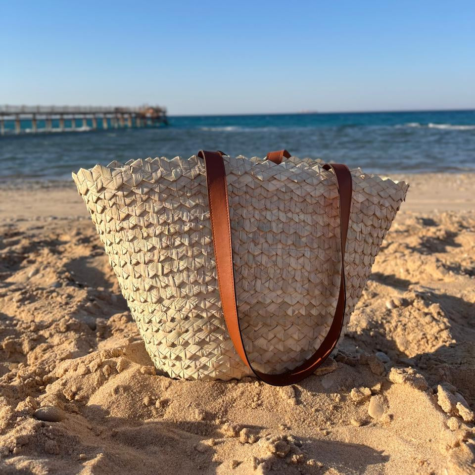Eco-Chic palm tote on the beach seen from a low angle, sea behind — Khoos