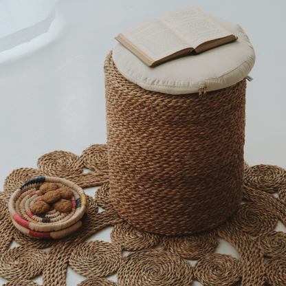 Halfa Rolled Comfort Stool with its cushion, styled on a woven rug with a book and a bowl of dates — Khoos