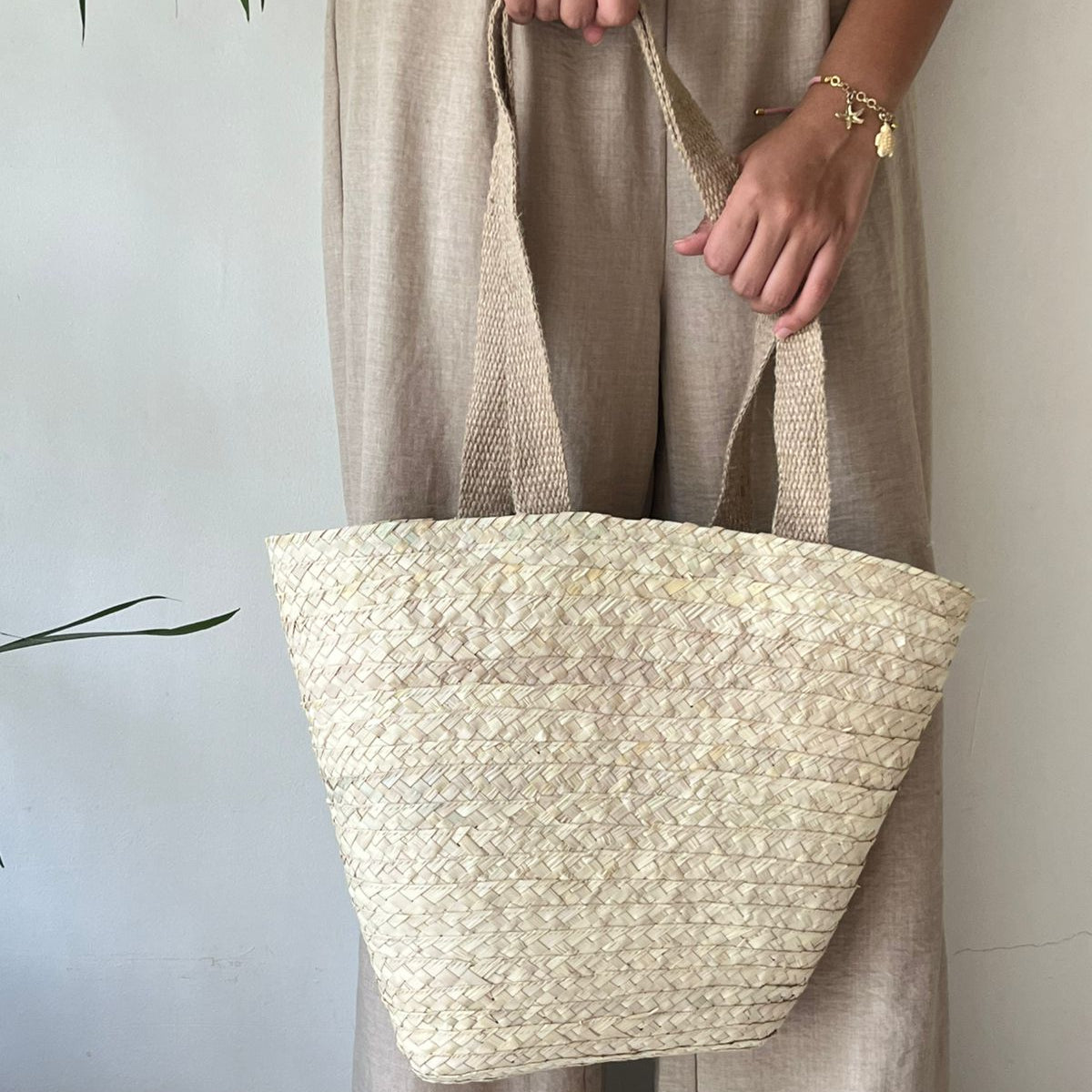 Plain woven beach tote carried at the side in linen clothing, close view of the body and handles — Khoos
