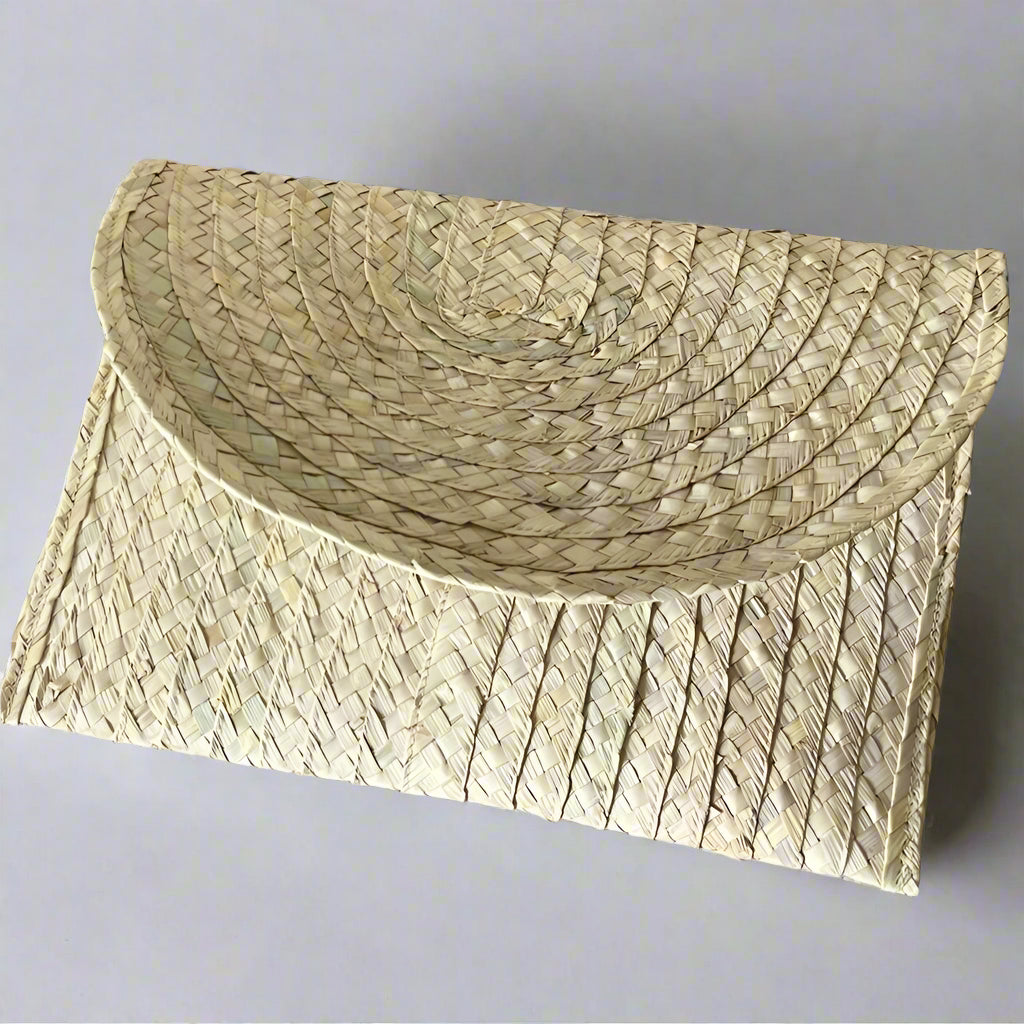 Angled view of the Sana clutch showing the flap edge and diamond lattice palm weave — Khoos