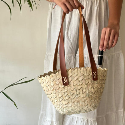 Wavy palm tote carried against a cream outfit, showing how it sits when worn — Khoos