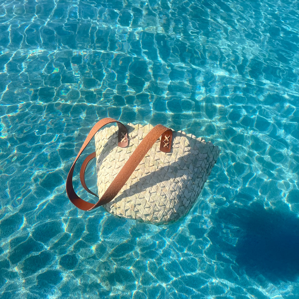 Wavy palm tote styled poolside on bright blue water — Khoos
